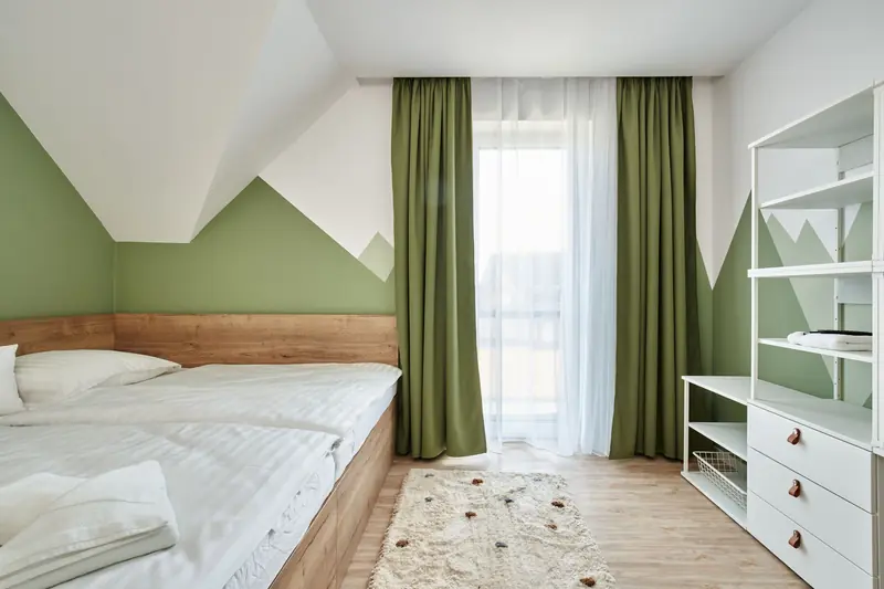 Ložnice s dvoulůžkem a zelenou stěnou