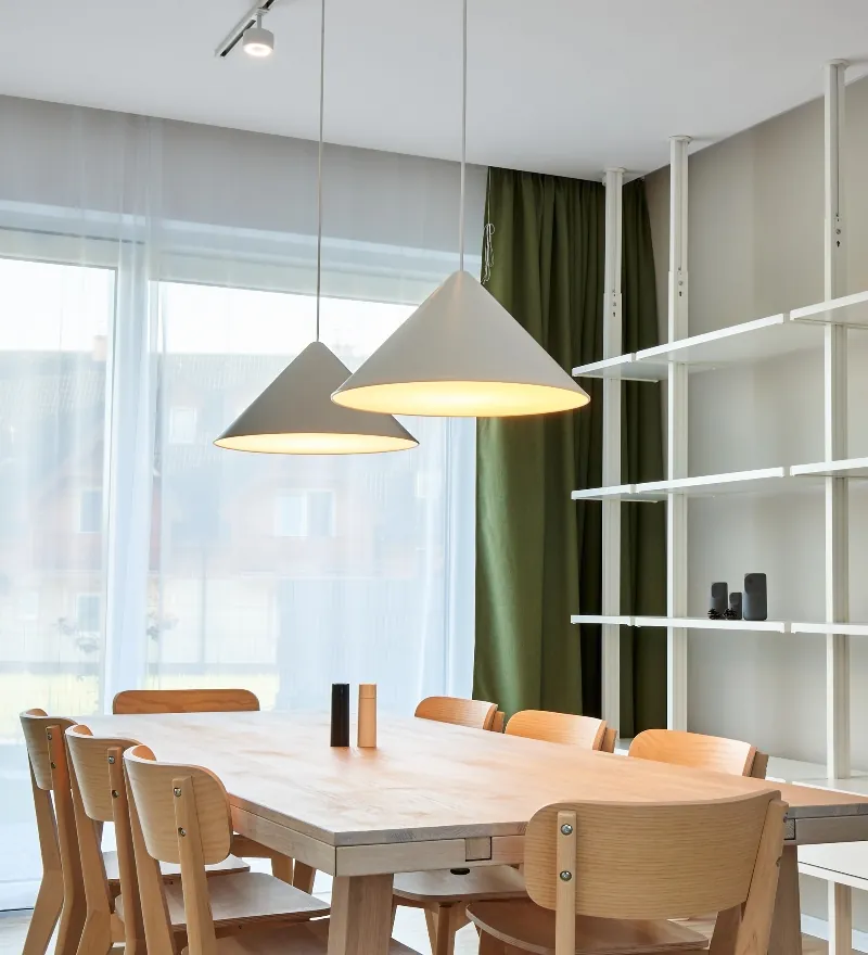 Jedáleň chaty Tatra Green s veľkým dreveným stolom a závesnými lampami